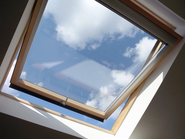 Ein geöffnetes sauberes Dachfenster mit Ausblick auf strahlenblauen Himmel