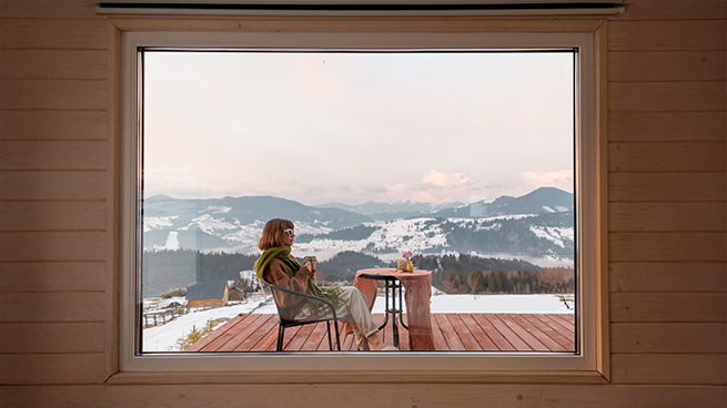 Großes Panoramafenster mit Ausblick auf schneebedeckte Berge