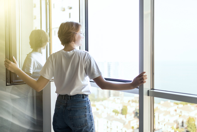 Frau öffnet ein Fenster um den Raum kontrolliert zu lüften