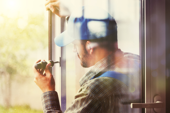 Ein Handwerker repariert ein Fenster oder eine Balkontüre.