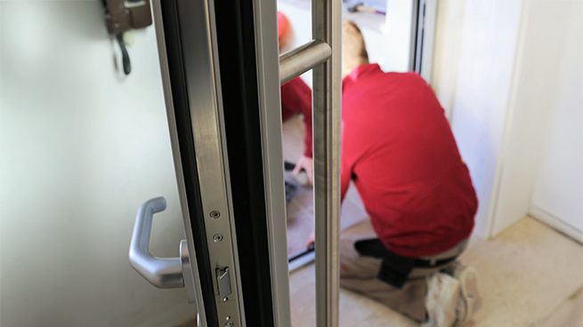 Handwerker saniert eine Haustüre im bestehenden Haus