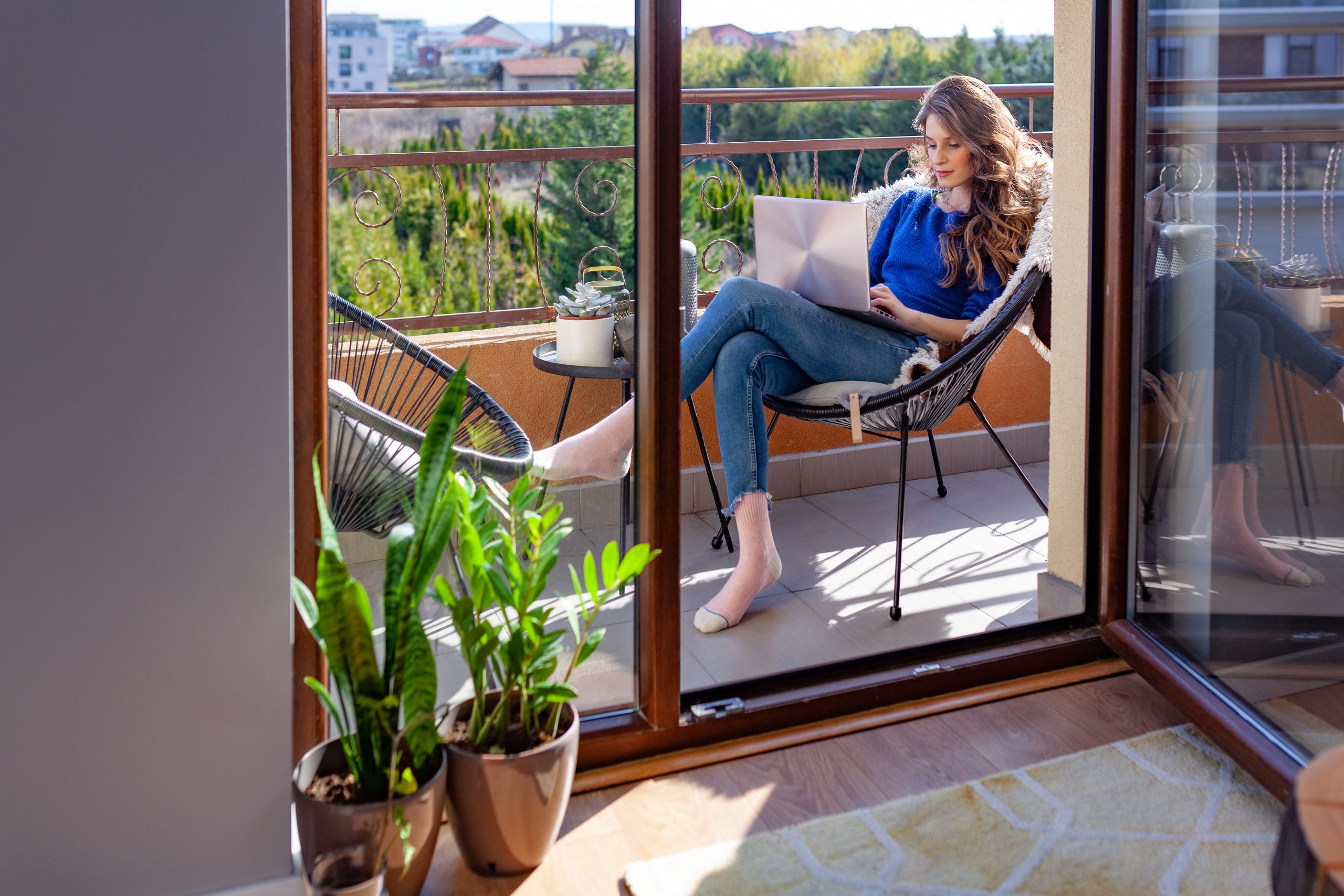 Porte-fenêtre en bois à deux battants menant à un petit balcon avec deux fauteuils et une table