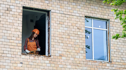 Handwerkerin tauscht ein Neues gegen ein Altes Fenster im Altbau aus