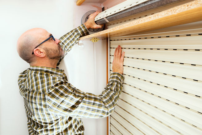 Mann steht vor geöffnetem Rollladenkasten