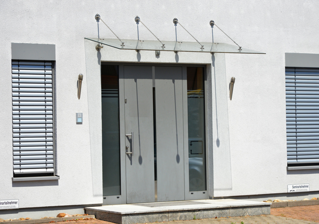 Porte d'entrée moderne avec panneaux latéraux et auvent à tirants en verre