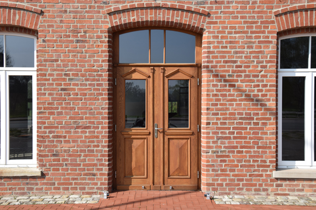 Eine zweiflügelige Holzhaustür mit Oberlicht in einer Backstein-Fassade