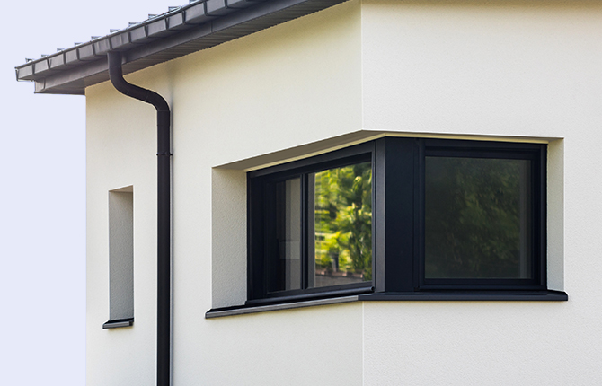 Fenêtre d’angle sombre en aluminium sur une maison moderne avec toit plat