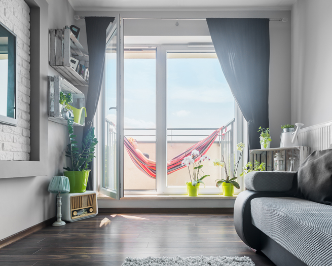 Porte-fenêtre d'une chambre moderne donnant sur une terrasse lumineuse