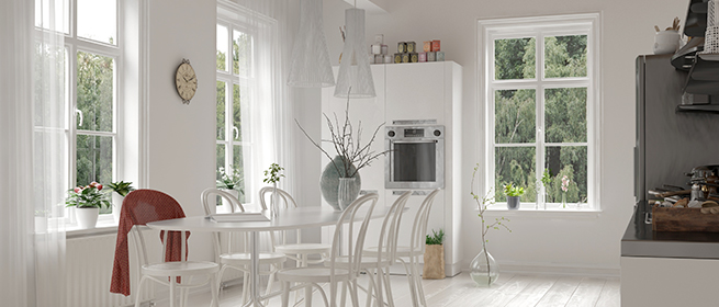 Une cuisine lumineuse avec une table à manger blanche et des chaises, ainsi que trois belles fenêtres à croisillons blanches