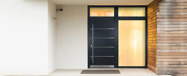 Porte en aluminium de couleur anthracite avec imposte et panneau latéral sur une façade de maison claire