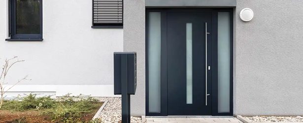 Porte d’entrée aluminium en couleur anthracite avec parties latérales sur une façade de maison grise