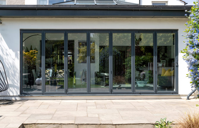 Porte pliante avec sept vantaux en gris anthracite et terrasse en terracotta