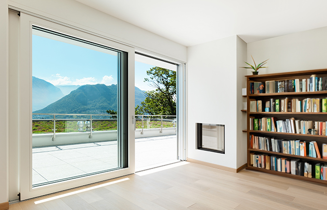 Vue à travers une baie levante-coulissant en PVC blanc avec un vantail ouvert sur des montagnes